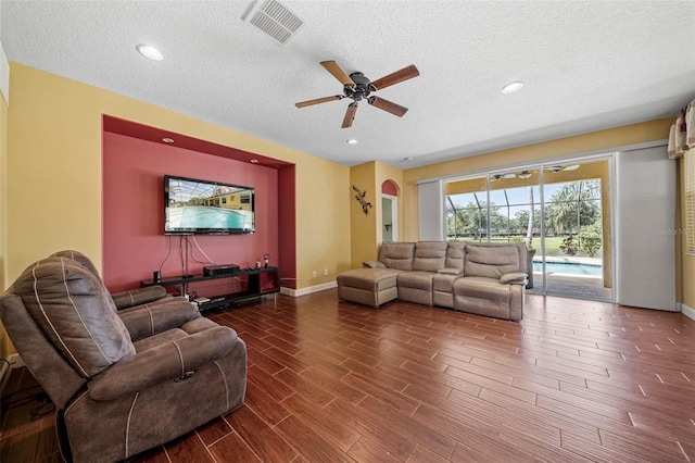 living room with a textured ceiling, ceiling fan, and dark hardwood / wood-style flooring