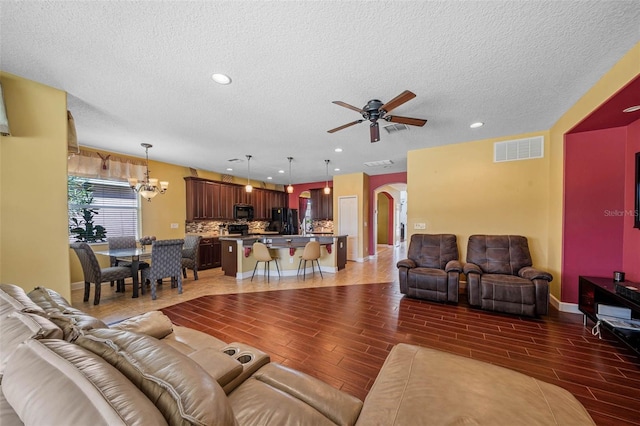 living room featuring a textured ceiling, dark hardwood / wood-style floors, and ceiling fan with notable chandelier