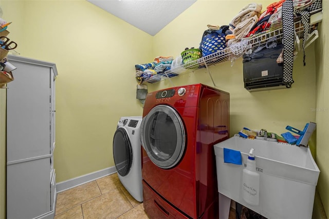 clothes washing area featuring sink, independent washer and dryer, and light tile patterned flooring