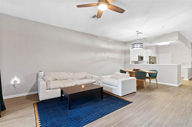 living room featuring ceiling fan and light hardwood / wood-style flooring