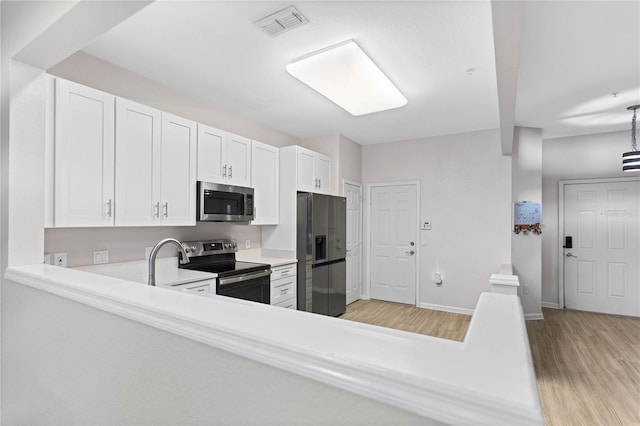 kitchen with light wood-type flooring, sink, appliances with stainless steel finishes, and white cabinets