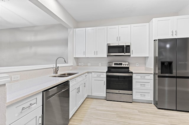 kitchen with appliances with stainless steel finishes, white cabinetry, and sink