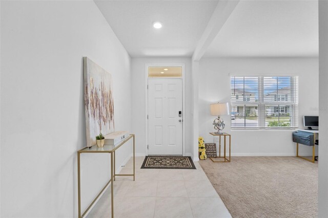 carpeted foyer featuring beam ceiling