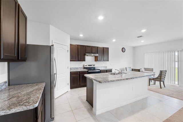 kitchen featuring dark brown cabinets, stainless steel appliances, an island with sink, sink, and light colored carpet