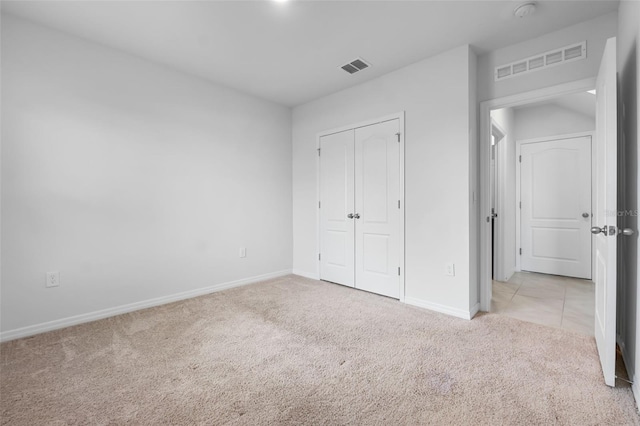 unfurnished bedroom featuring light colored carpet and a closet