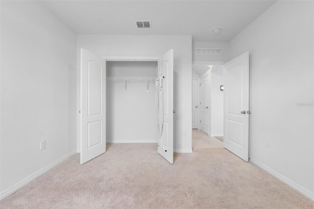 unfurnished bedroom with light carpet and a closet