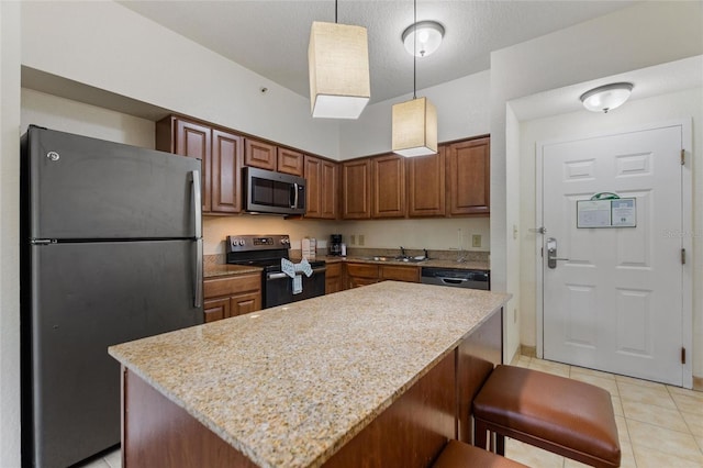 kitchen with decorative light fixtures, stainless steel appliances, a kitchen island, sink, and light stone countertops