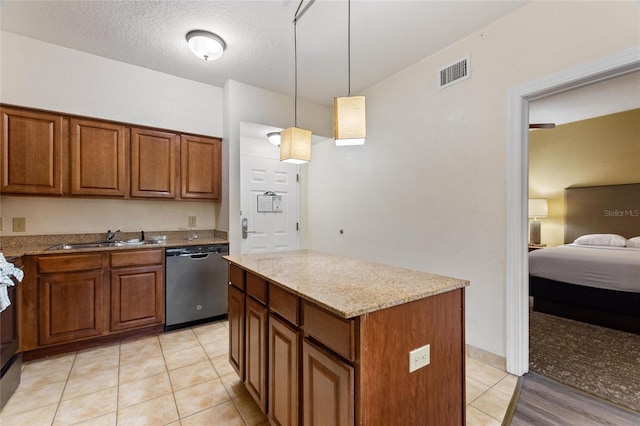 kitchen with a kitchen island, pendant lighting, stainless steel dishwasher, sink, and light stone counters