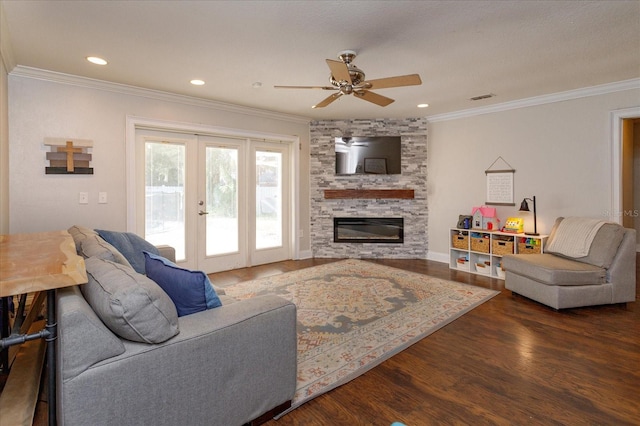 living room with a stone fireplace, dark hardwood / wood-style flooring, crown molding, ceiling fan, and french doors