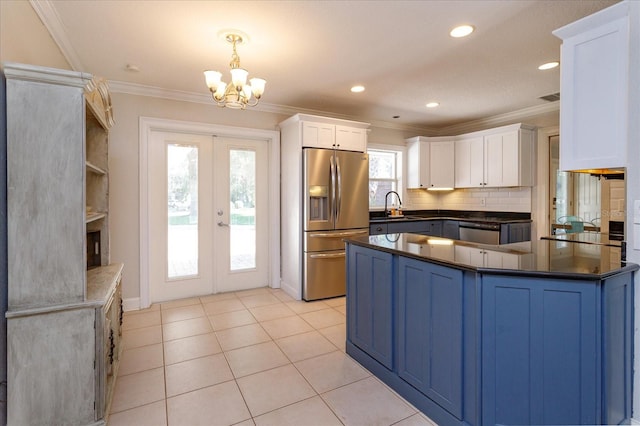 kitchen with hanging light fixtures, white cabinets, stainless steel appliances, sink, and a notable chandelier