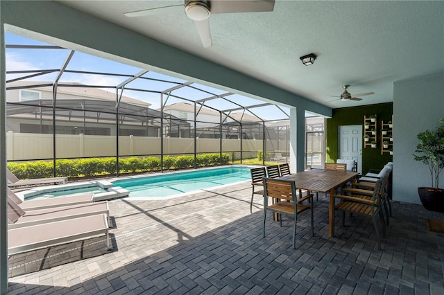 view of swimming pool featuring glass enclosure, ceiling fan, and a patio area