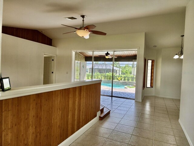 interior space featuring ceiling fan, light tile patterned flooring, and vaulted ceiling