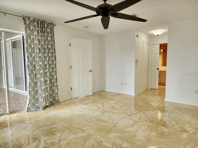 empty room featuring marble finish floor, a ceiling fan, and baseboards