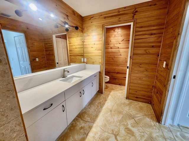 bathroom featuring wooden walls, toilet, vanity, and visible vents