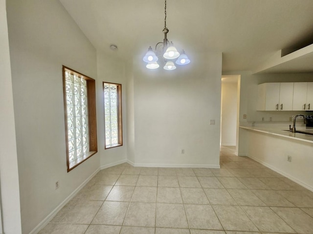 unfurnished dining area with an inviting chandelier, light tile patterned floors, baseboards, and a sink