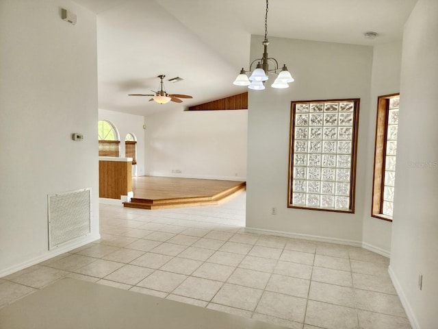 spare room featuring light tile patterned floors, visible vents, lofted ceiling, and ceiling fan with notable chandelier