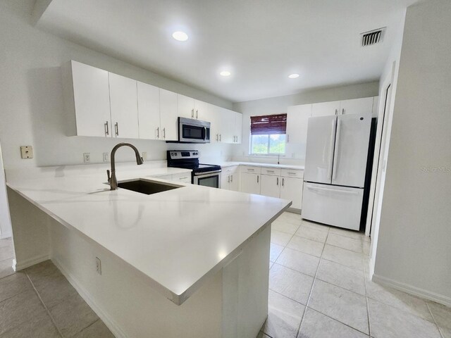 kitchen featuring light tile patterned floors, appliances with stainless steel finishes, kitchen peninsula, sink, and white cabinets