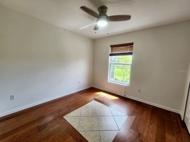 empty room with baseboards, wood finished floors, and a ceiling fan