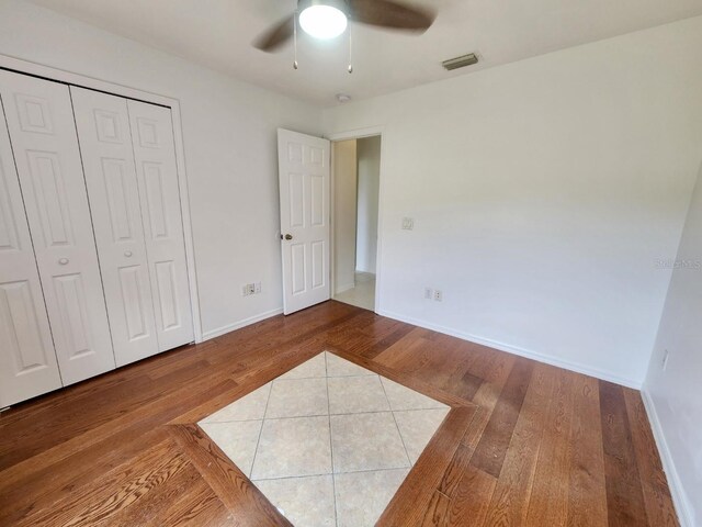 unfurnished bedroom with hardwood / wood-style floors, ceiling fan, and a closet