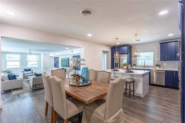 dining area featuring dark wood-type flooring, a textured ceiling, and a wealth of natural light