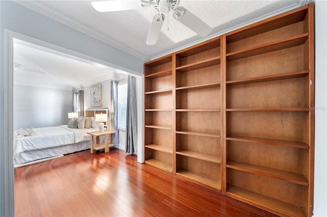 bedroom with ceiling fan, ornamental molding, wood-type flooring, and a textured ceiling