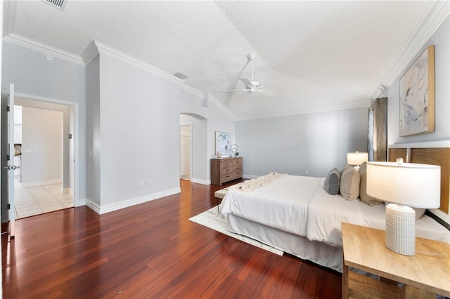 bedroom featuring ceiling fan, wood-type flooring, a textured ceiling, vaulted ceiling, and ornamental molding