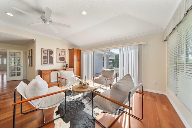 living room featuring ceiling fan, light hardwood / wood-style floors, a textured ceiling, lofted ceiling, and ornamental molding