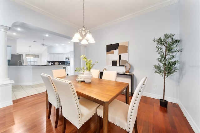 dining space with a chandelier, decorative columns, and light hardwood / wood-style flooring