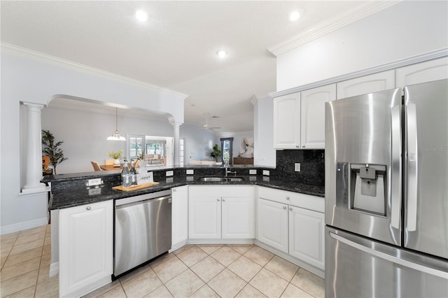 kitchen featuring sink, appliances with stainless steel finishes, white cabinets, dark stone counters, and ornate columns