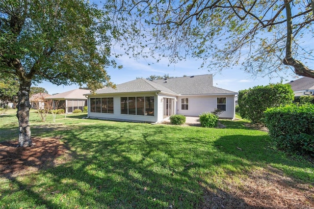 back of property with a sunroom and a lawn