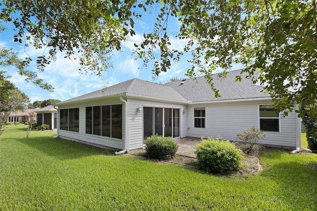 back of house featuring a lawn, a sunroom, and a patio area