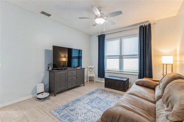 living room with ceiling fan, light tile patterned floors, and a textured ceiling