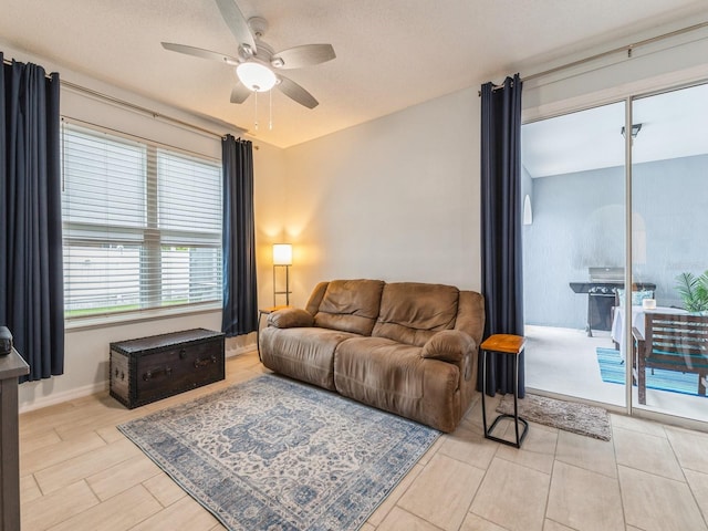 living room featuring ceiling fan and a textured ceiling