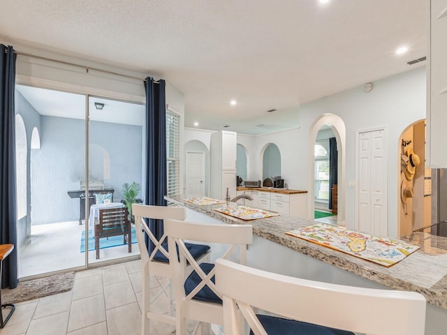 interior space with light tile patterned floors, white cabinetry, and a textured ceiling