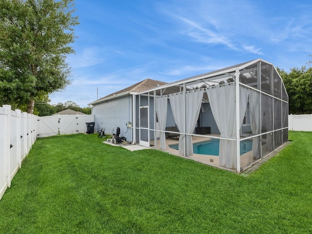 rear view of property featuring a fenced in pool, a lanai, and a yard