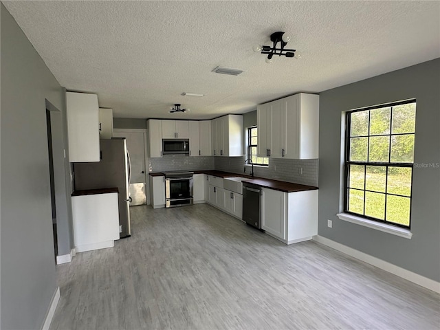 kitchen with dark countertops, visible vents, backsplash, and stainless steel appliances