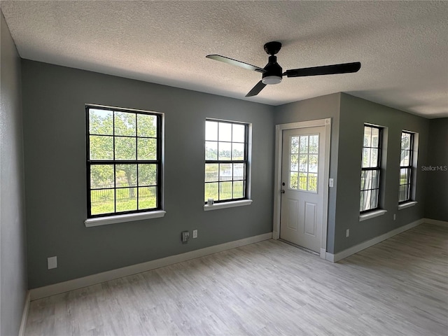 interior space with baseboards, a textured ceiling, wood finished floors, and a ceiling fan