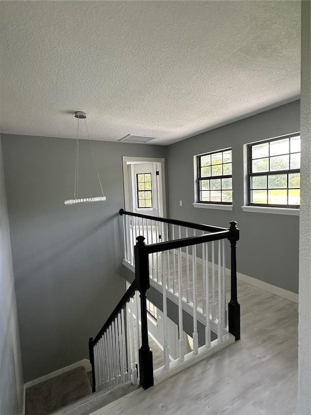 stairs with a textured ceiling, baseboards, and wood finished floors