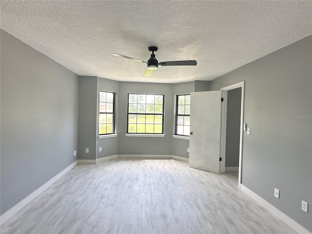 unfurnished room with baseboards, light wood-style floors, ceiling fan, and a textured ceiling