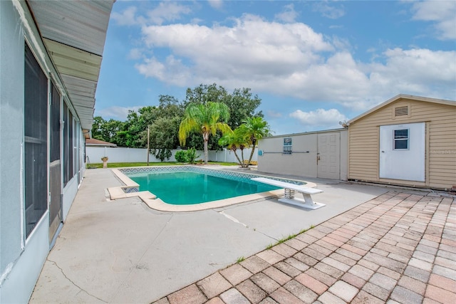 view of swimming pool with a diving board, a patio, and a storage shed