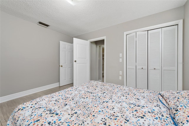 bedroom with a textured ceiling, a closet, and hardwood / wood-style flooring