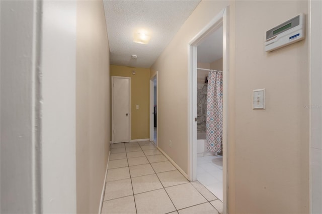 hall with light tile patterned floors and a textured ceiling