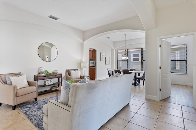 tiled living room with a notable chandelier