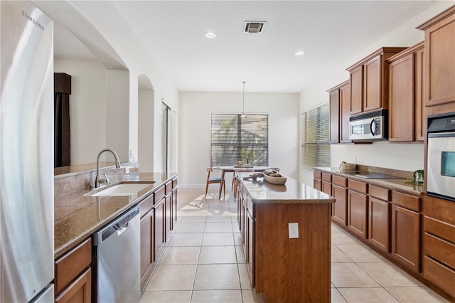 kitchen featuring a center island, appliances with stainless steel finishes, sink, light tile patterned flooring, and pendant lighting