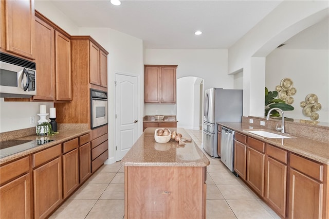 kitchen featuring a center island, stainless steel appliances, sink, and light tile patterned flooring