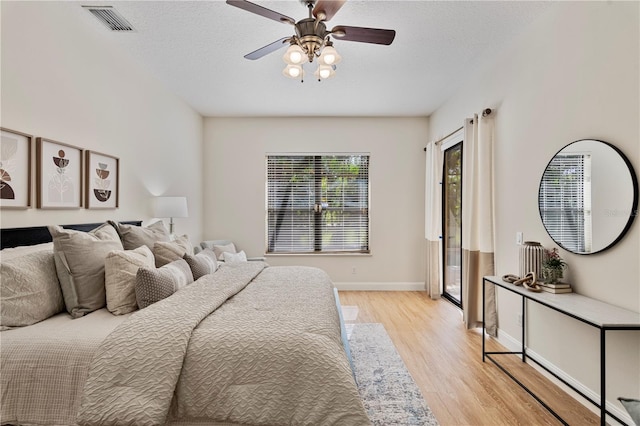 bedroom with light wood-type flooring, ceiling fan, and a textured ceiling