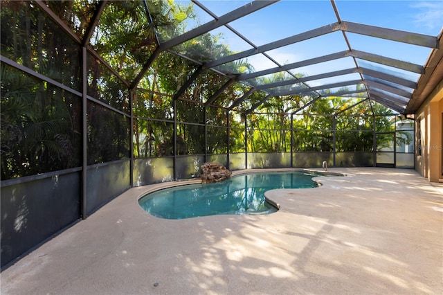 view of pool with glass enclosure and a patio area