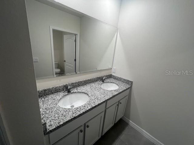 bathroom with toilet, vanity, and tile patterned floors