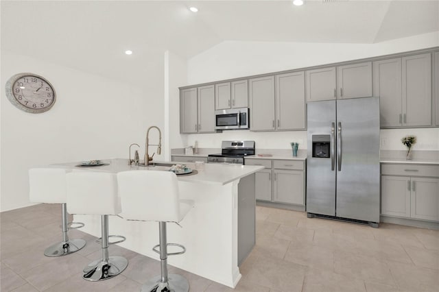 kitchen featuring lofted ceiling, a kitchen island with sink, sink, a breakfast bar area, and stainless steel appliances