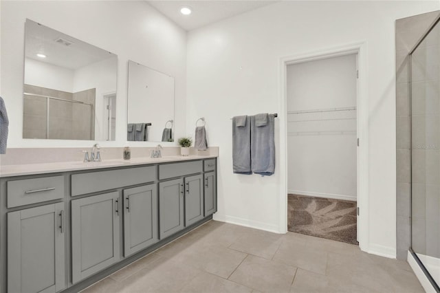 bathroom featuring tile patterned flooring, vanity, and a shower with door